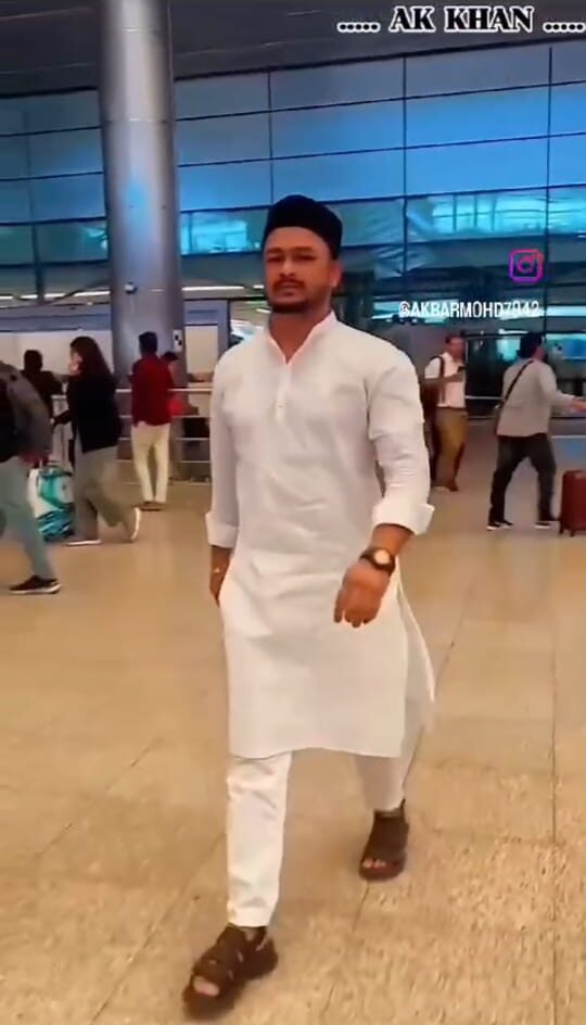 An individual wearing a white kurta-pajama and cap at the airport, heading for a business meeting – related to akkhanrealestate