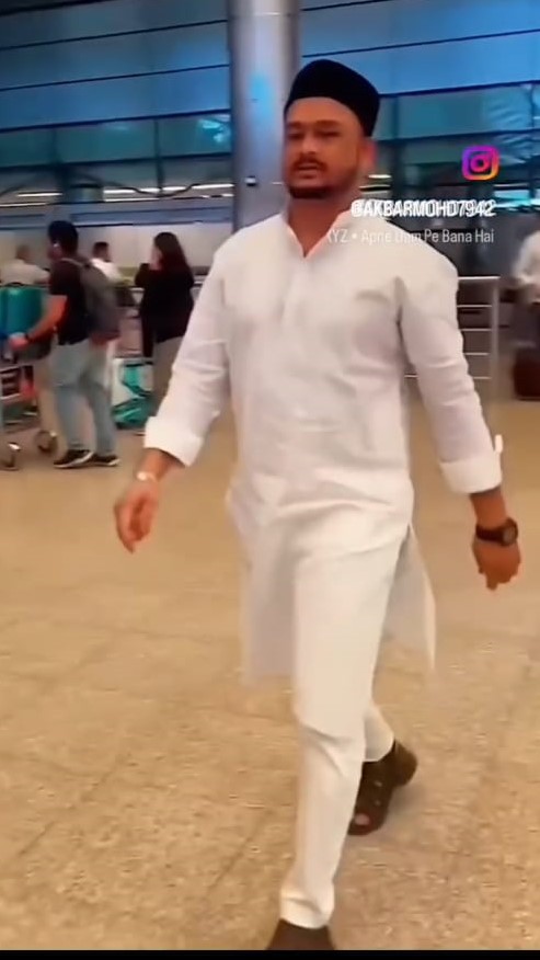 An individual wearing a white kurta-pajama and cap at the airport, heading for a business meeting – related to Ak khan real estate